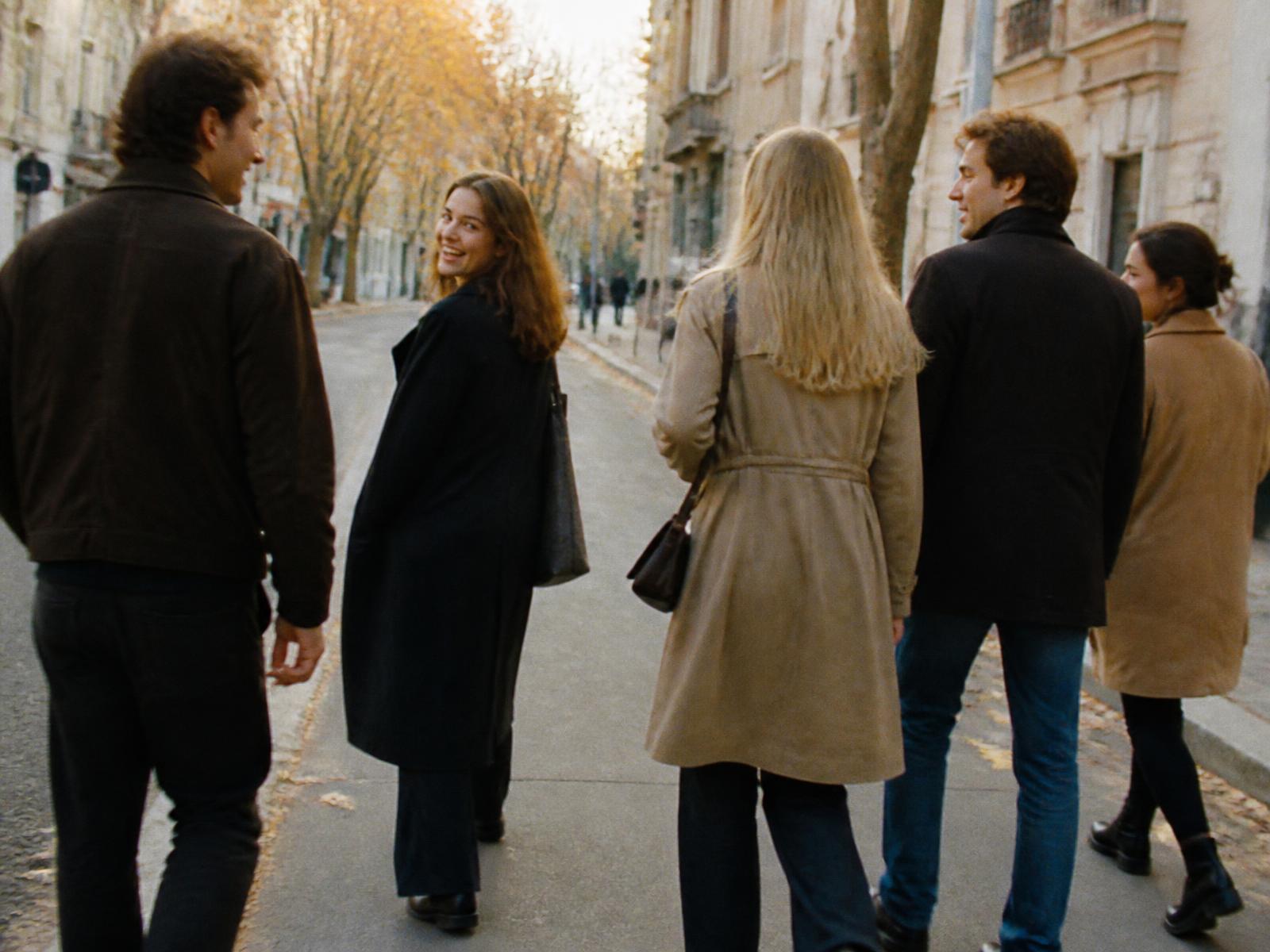 Five adults walking and talking along a quiet city street in late afternoon light